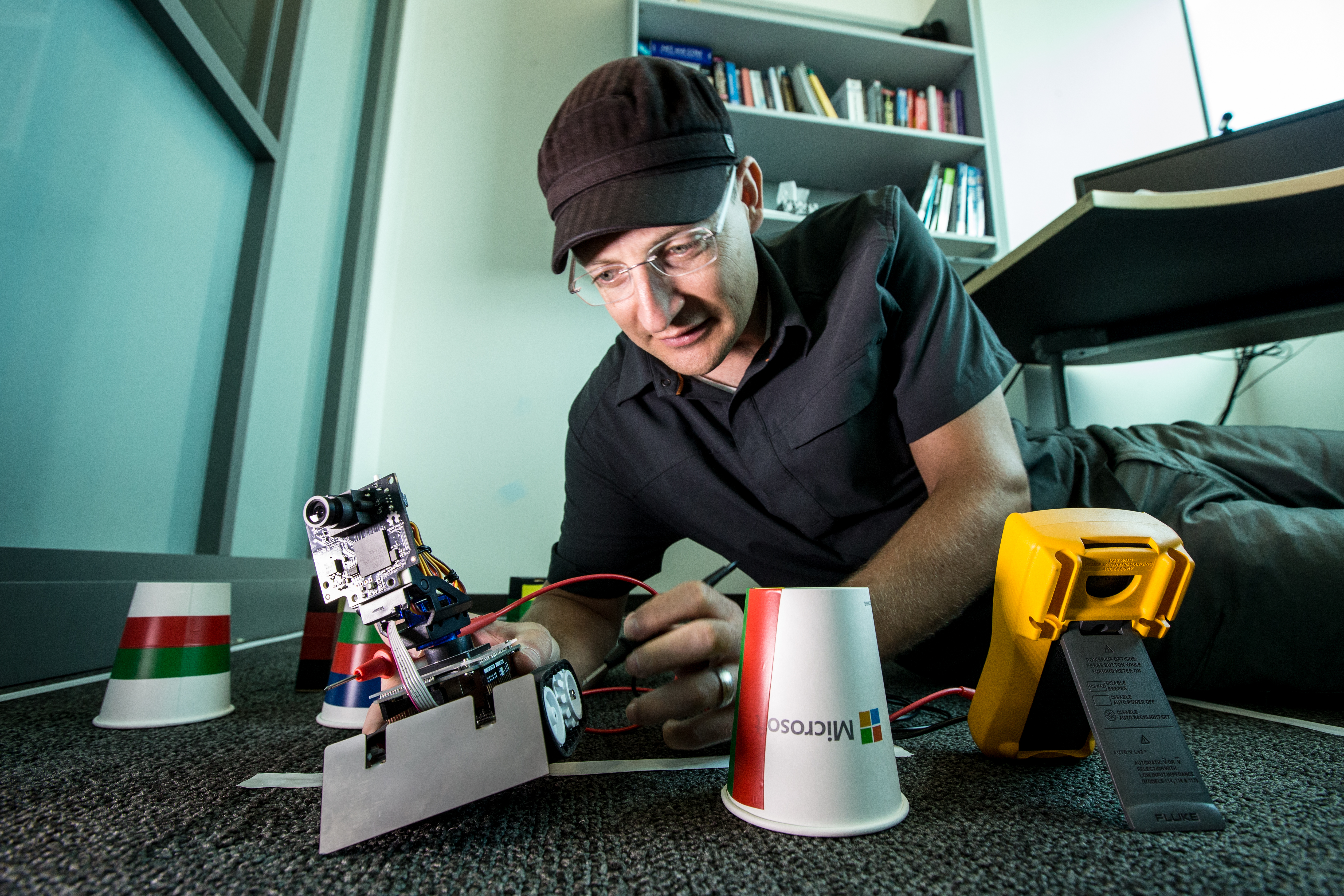 Frederick Fourie presents Argonaut, the robot his team is using to demonstrate how Windows 10 and the cloud can help devices like this do more around the house. The cups and tape represent a simple home layout and colors and lines that the robot is programmed to recognize. (Photo by Scott Eklund/Red Box Pictures.)