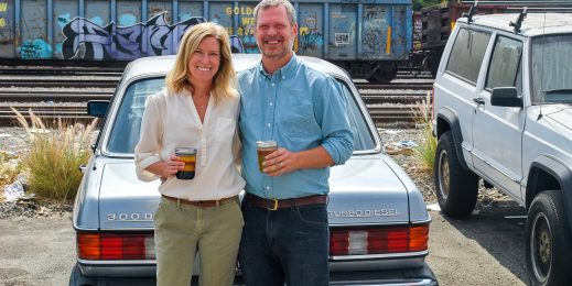 Megan and Marshall Dostal hold jars of grease in front of Marshall's Mercedes 300D