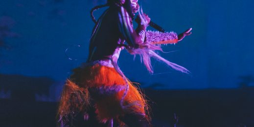 Donald Glover dressed in tribal garb, singing on stage