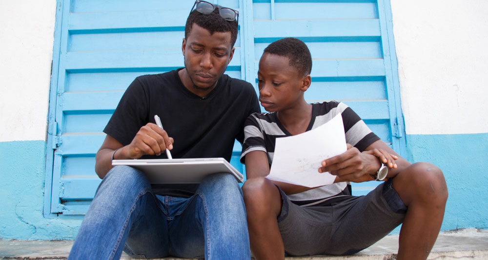 Artist Osa Seven, left, and Marvellous Adewopo work on a sketch for the mural they created together