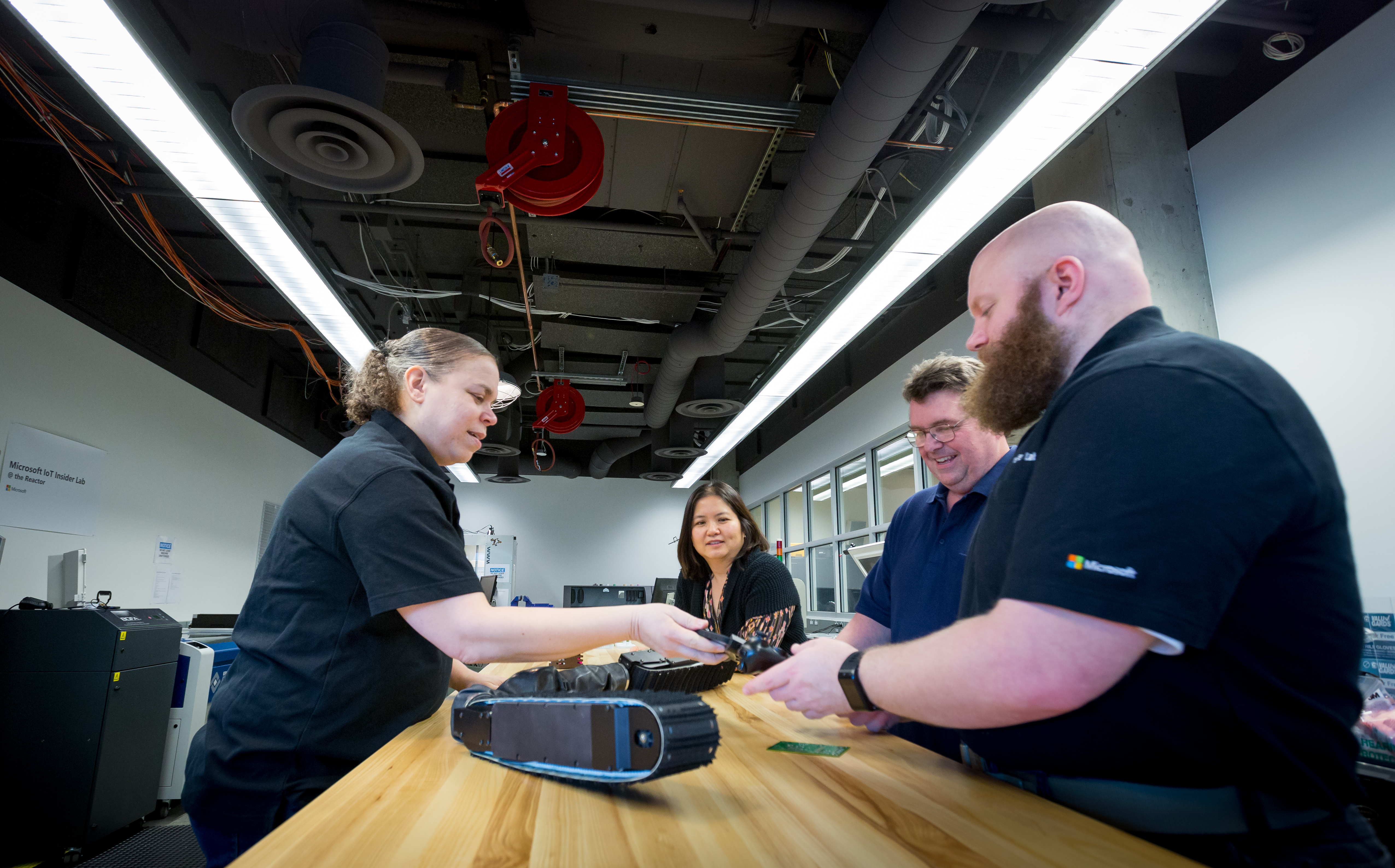 Cyra Richardson (left) stands opposite the workbench from (right to left) Barron Barnett, Sean Kelly and Marlina Hales as they examine a robot snake.