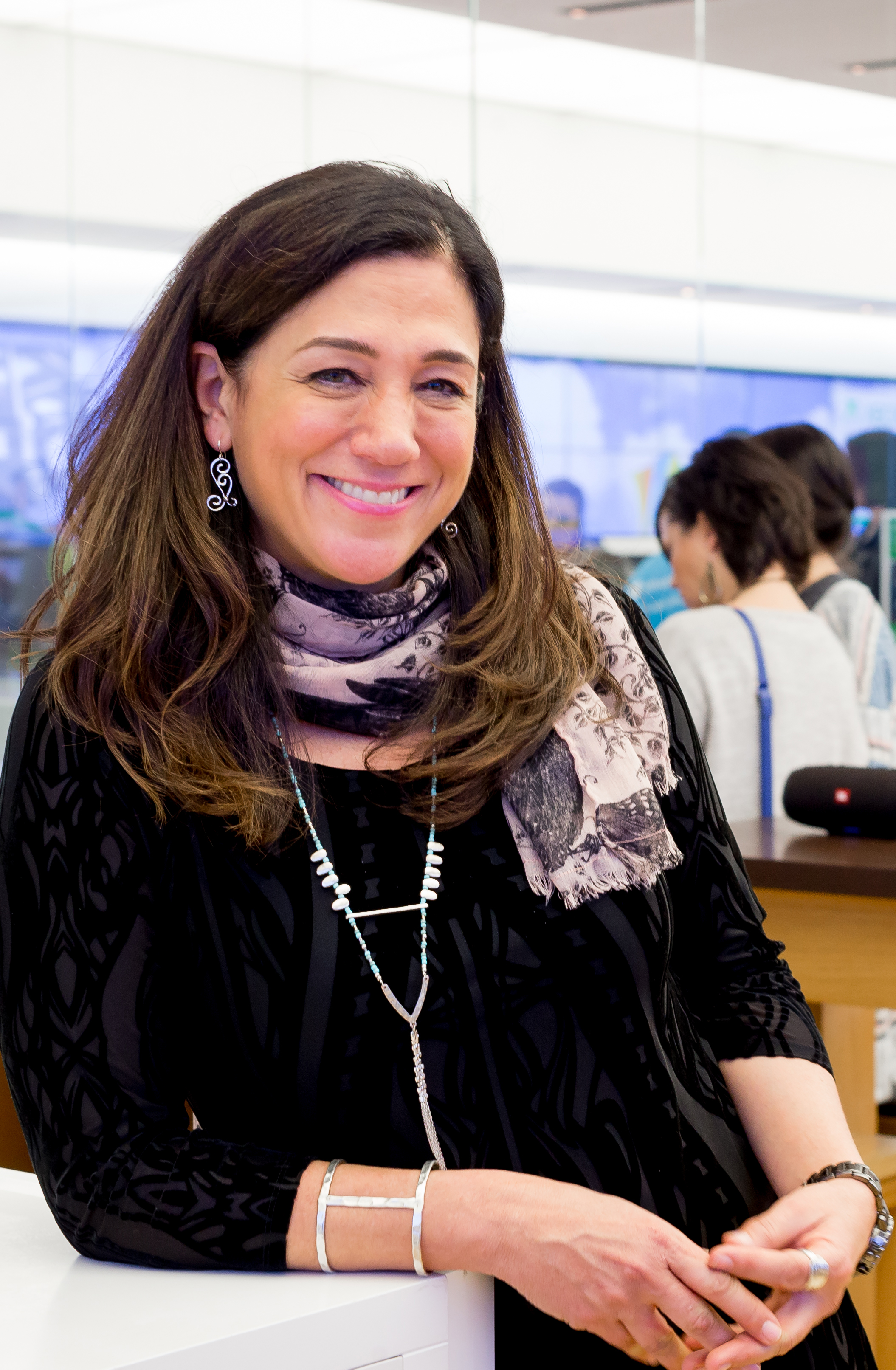 Photo of dark-haired woman smiling and leaning against table