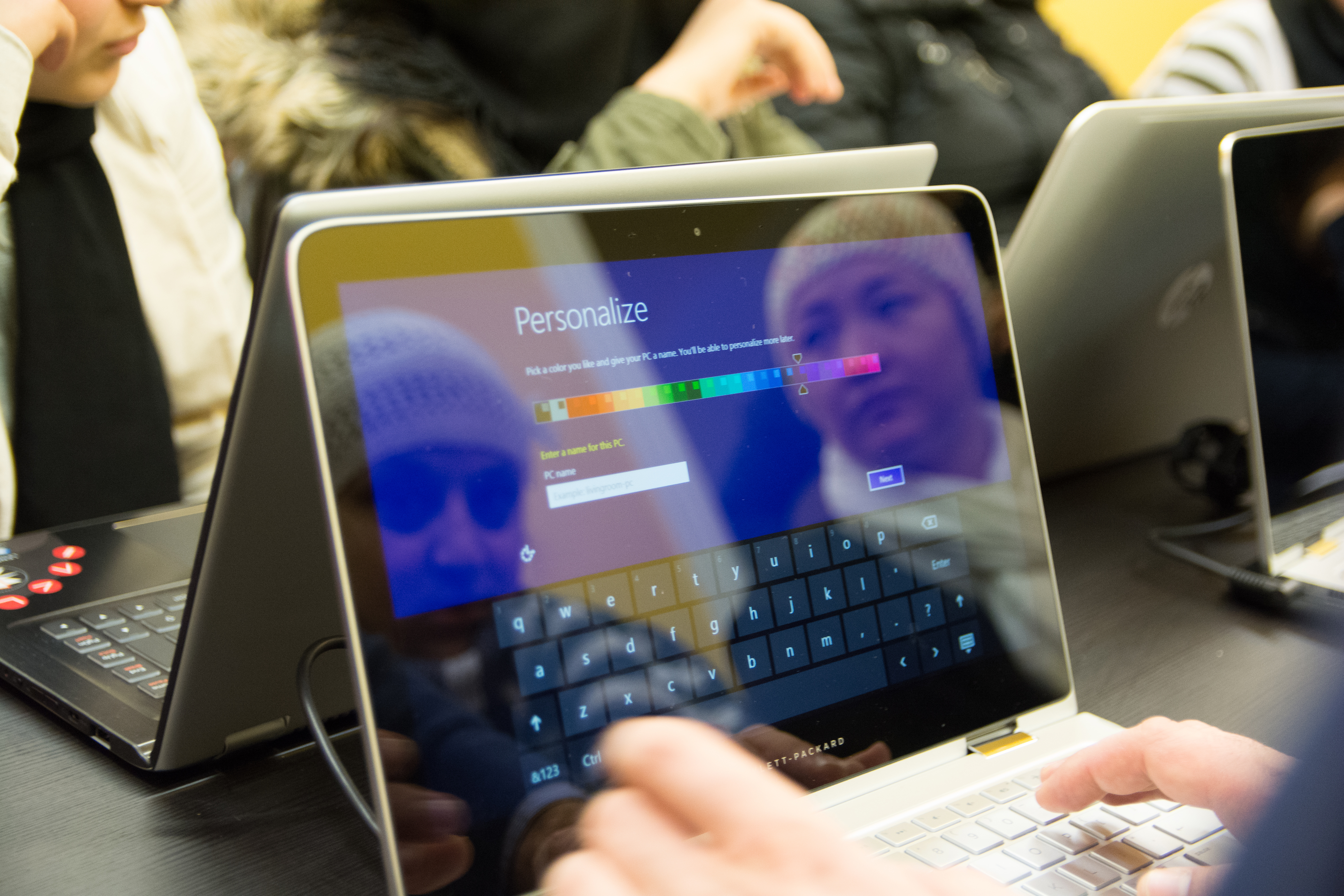 The reflection of two female refugees' faces in a computer screen, as they learn new computer skills