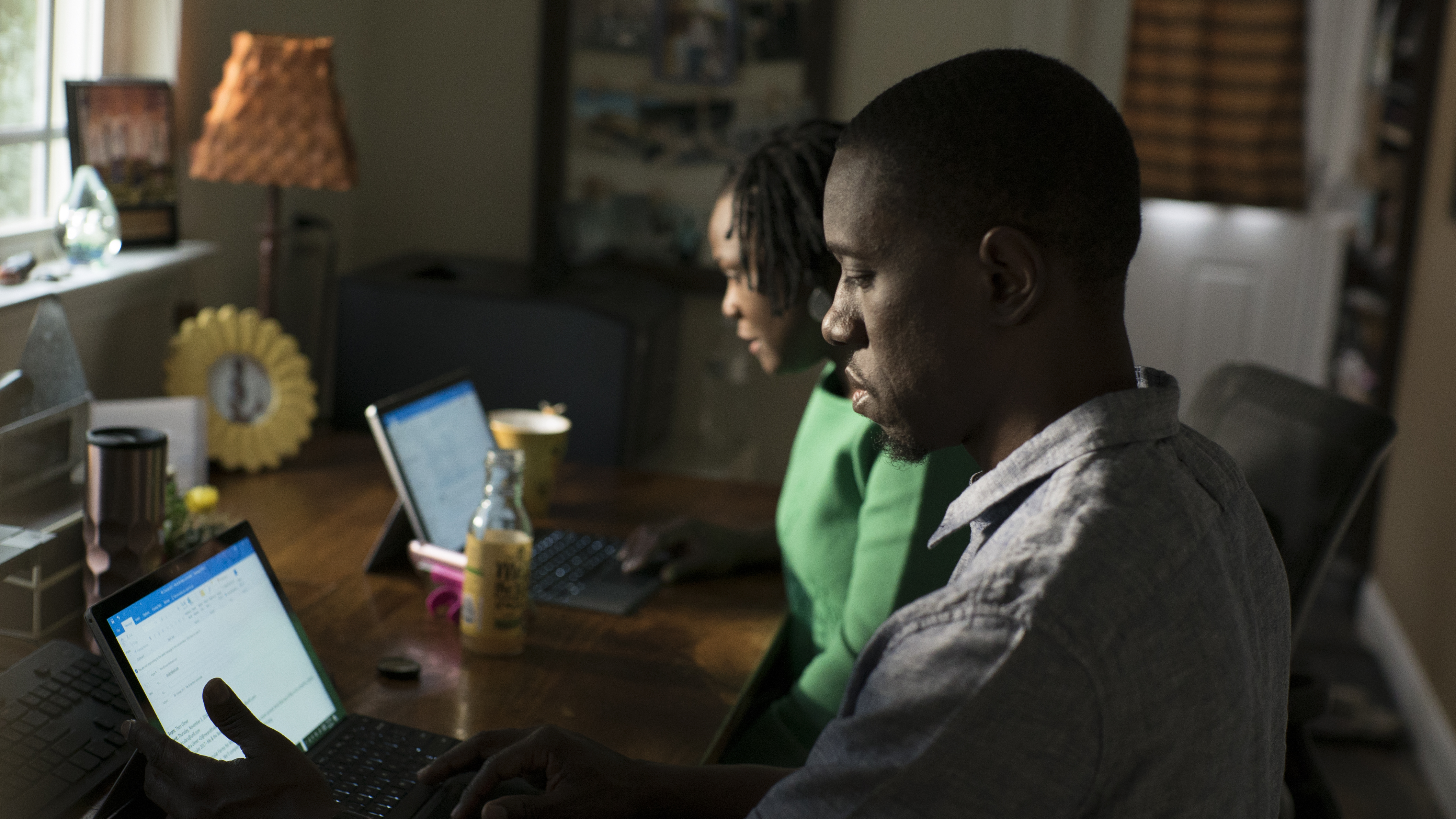 Photo of man and woman working side by side on laptops.