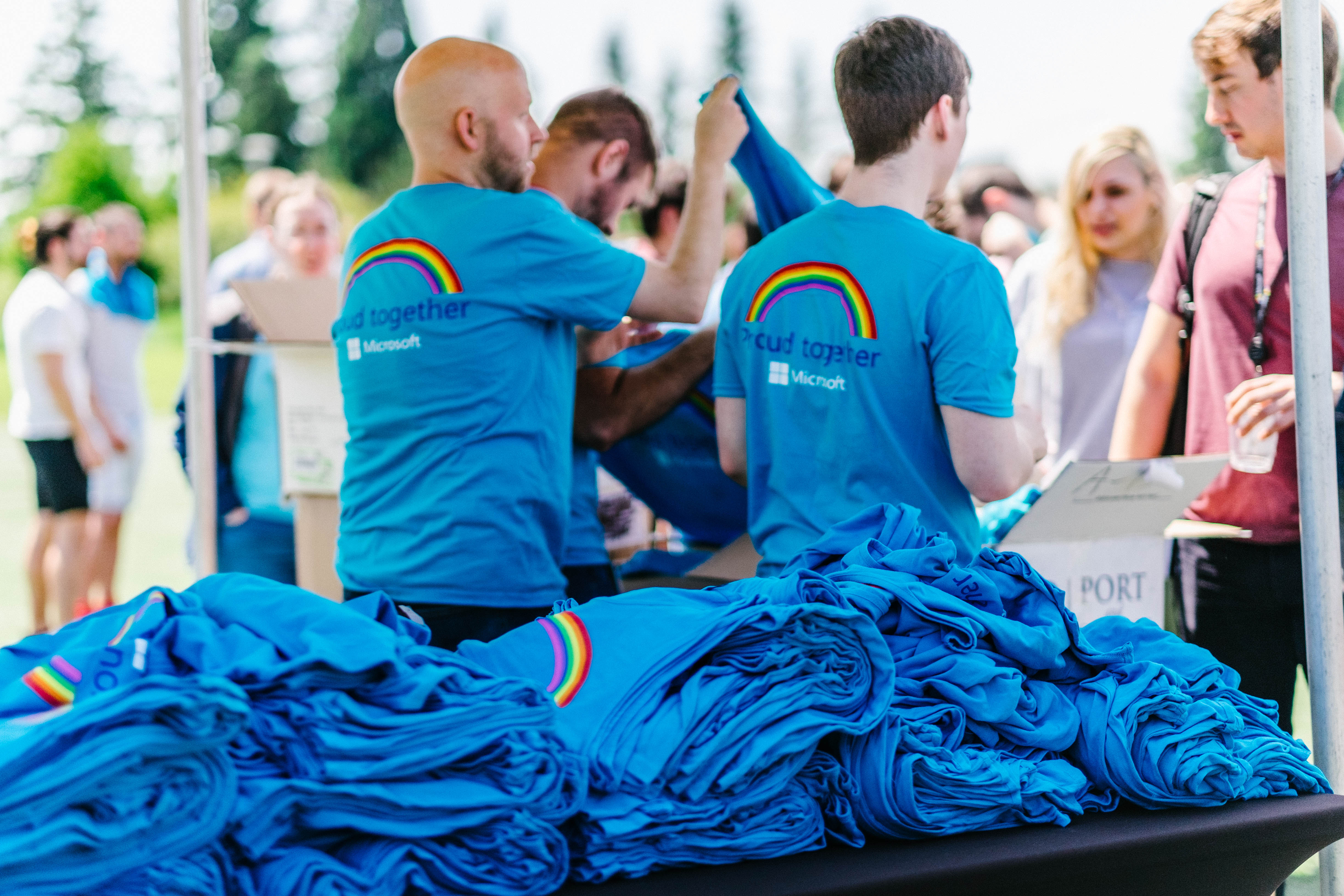 Photo of two men in a booth handing out T-shirts.