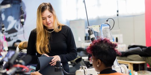 Veronika Scott, founder of the Empowerment Plan, discusses a project with a seamstress who's sitting at a sewing machine.