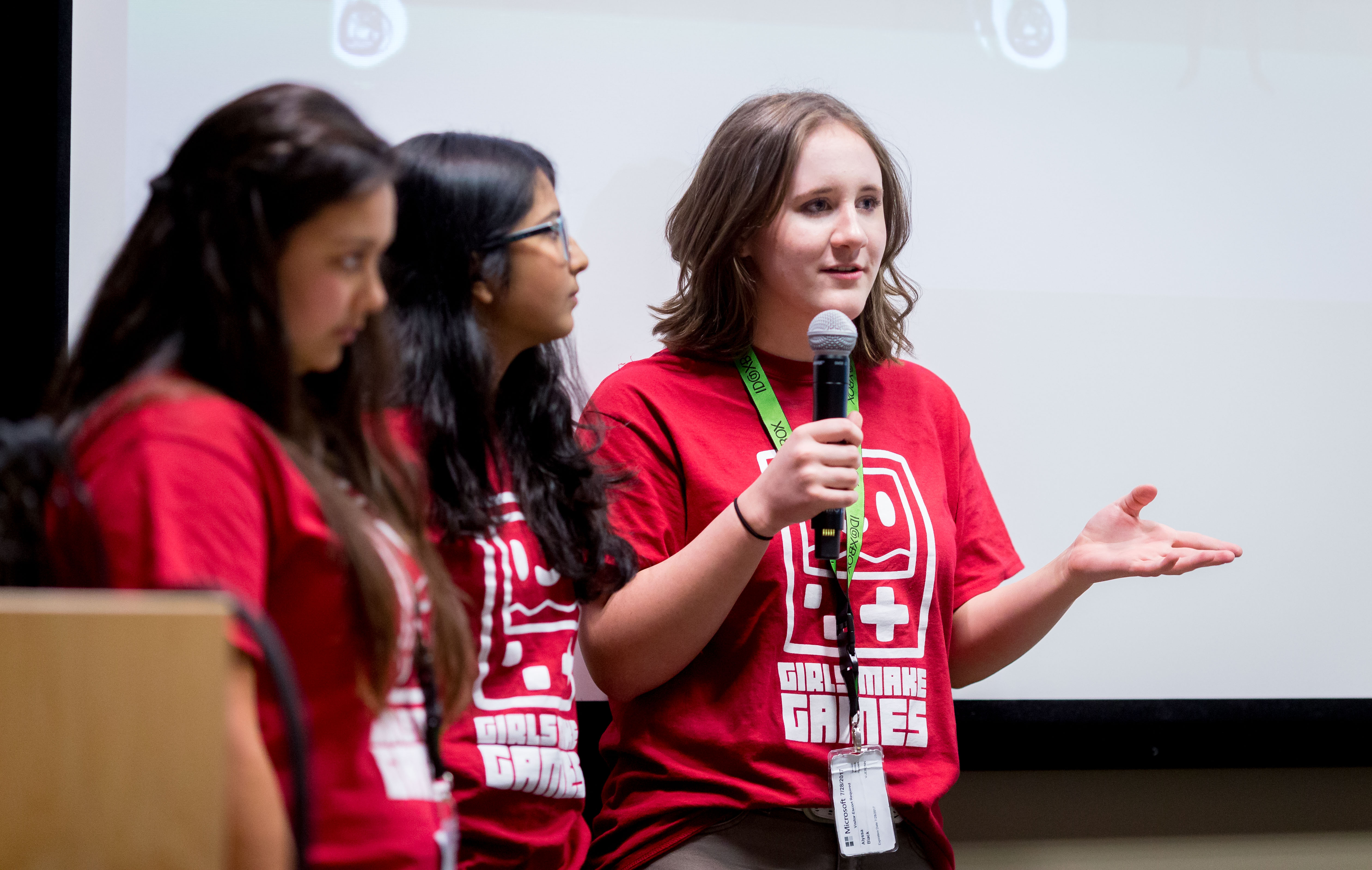 Three participants at Girls Make Games camp presenting their game to an audience