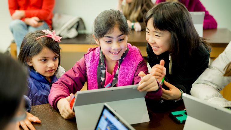 three little girls gather around a laptop