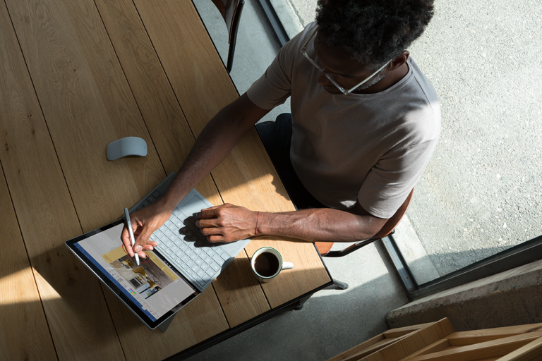 A man uses a Surface tablet at his kitchen table