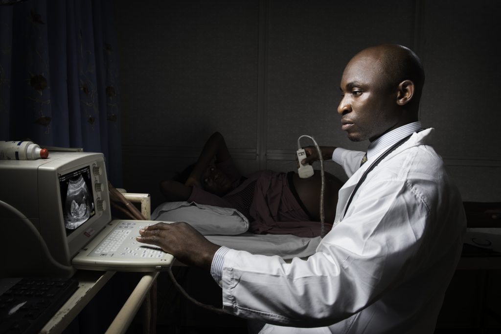 Doctor sitting beside a pregnant patient, performing an ultrasound