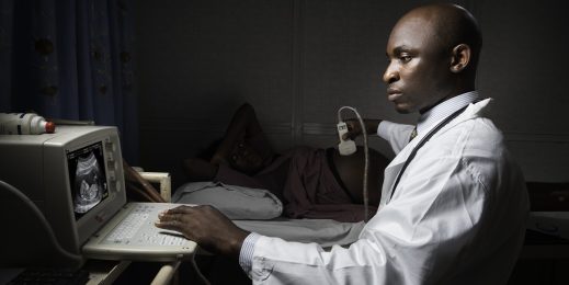 Doctor sitting beside a pregnant patient, performing an ultrasound