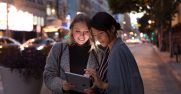Two women use Surface Go on a dark street