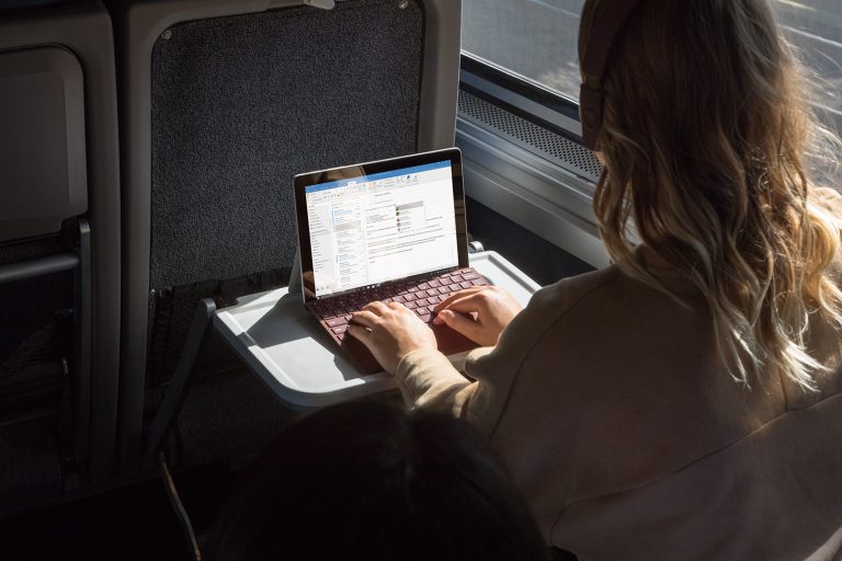 A woman uses a Surface Go on a train