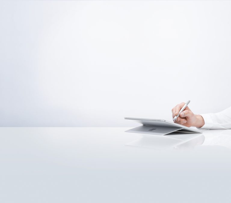 A hand writes on a Surface device