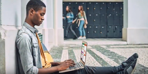 student sits on hallway floor with laptop