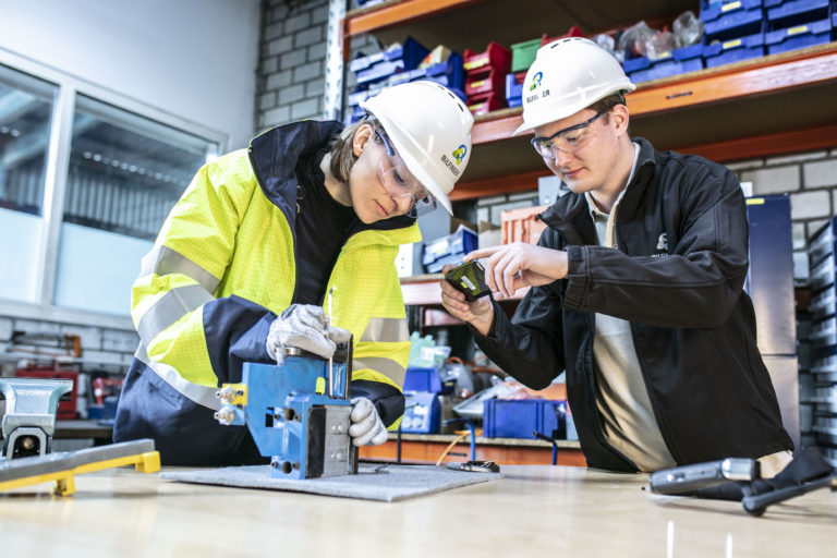 a man and a woman work on a piece of equipment