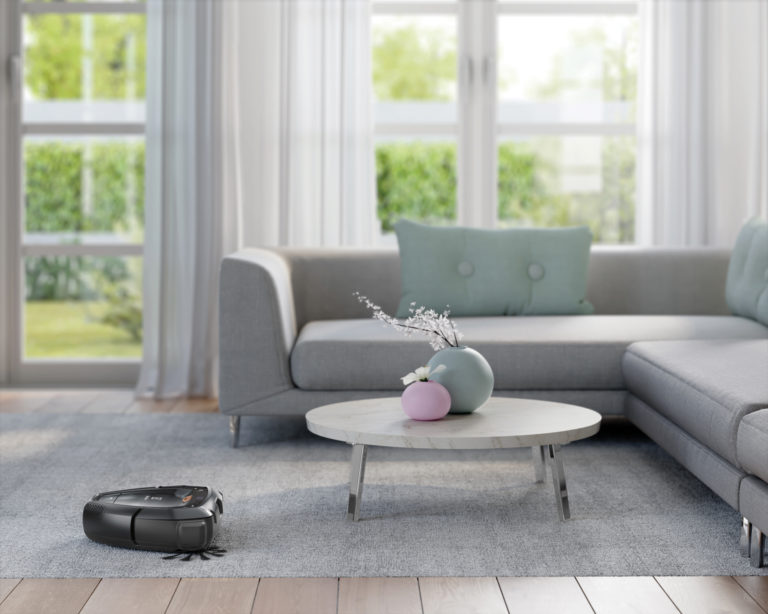 A Pure i9 cleans a rug and flooring while navigating a table and sofa.