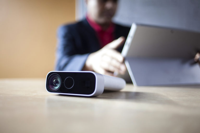 a man works on a surface device with an azure kinect in the foreground