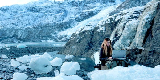 Jody MacDonald working on her HP with a backdrop of mountains and ice in Alaska