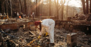 A woman picks up debris at the site of a burned building