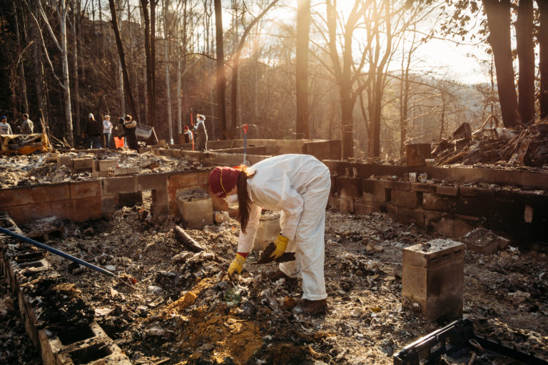 A woman picks up debris at the site of a burned building
