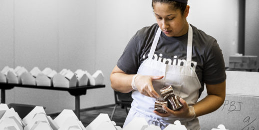 Female volunteer in apron packing lunches