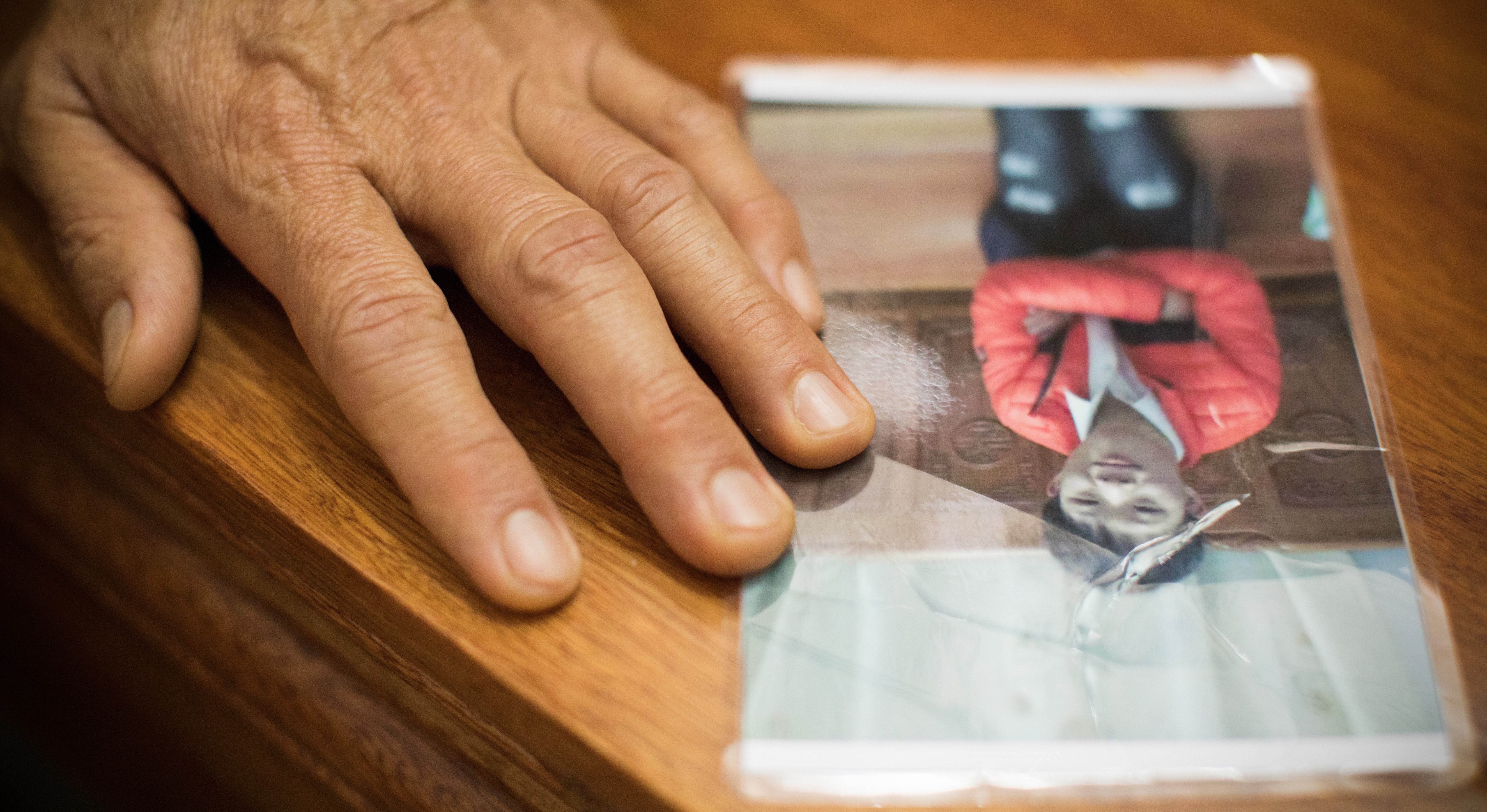 Photo of man's hand on photograph of a boy.