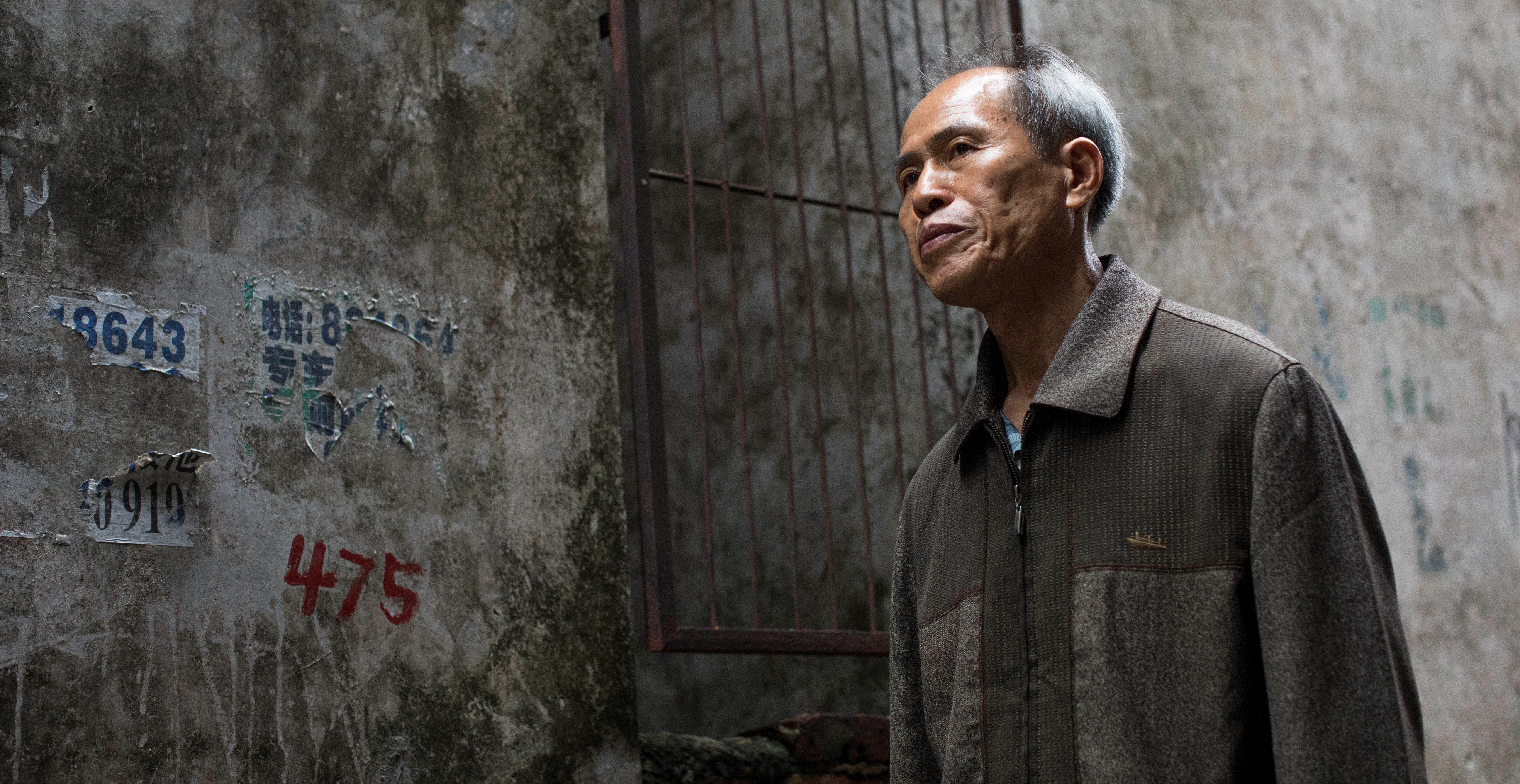 Photo of man walking past a concrete building in China.