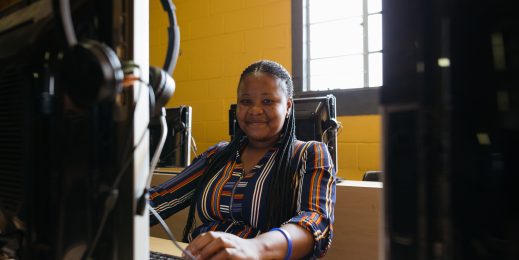 A woman smiles as she works on a computer in a nonprofit office in South Africa
