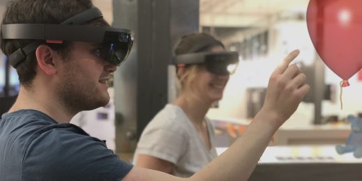 Person wearing HoloLens device reaches toward balloon
