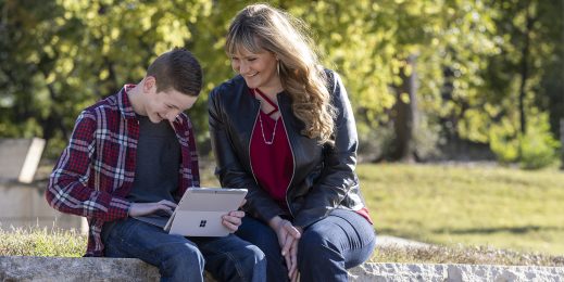 A child using a tablet with their mother sitting next to them