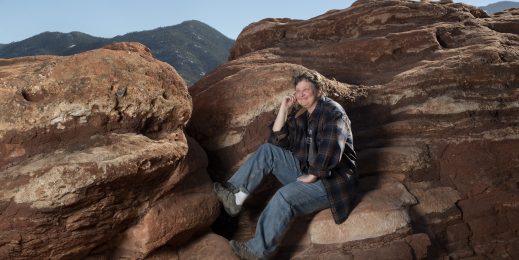 Smiling woman sitting on a rock in the outdoors