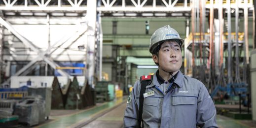 A man stands in front of a factory floor