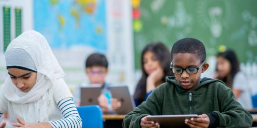 Childrens setting in class room and looking on a Tablet