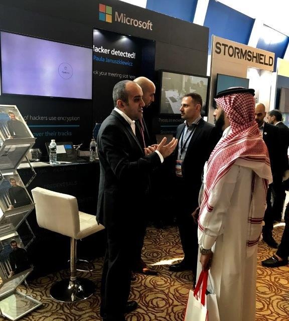 Group of men talking while standing by the Microsoft booth at the event