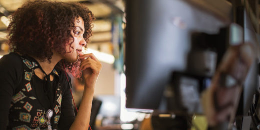 a woman sitting in an office environment working on her computer.