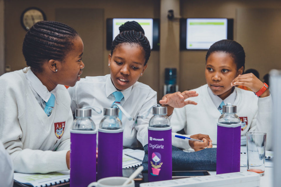 Three girls wearing school uniform sitting at a table