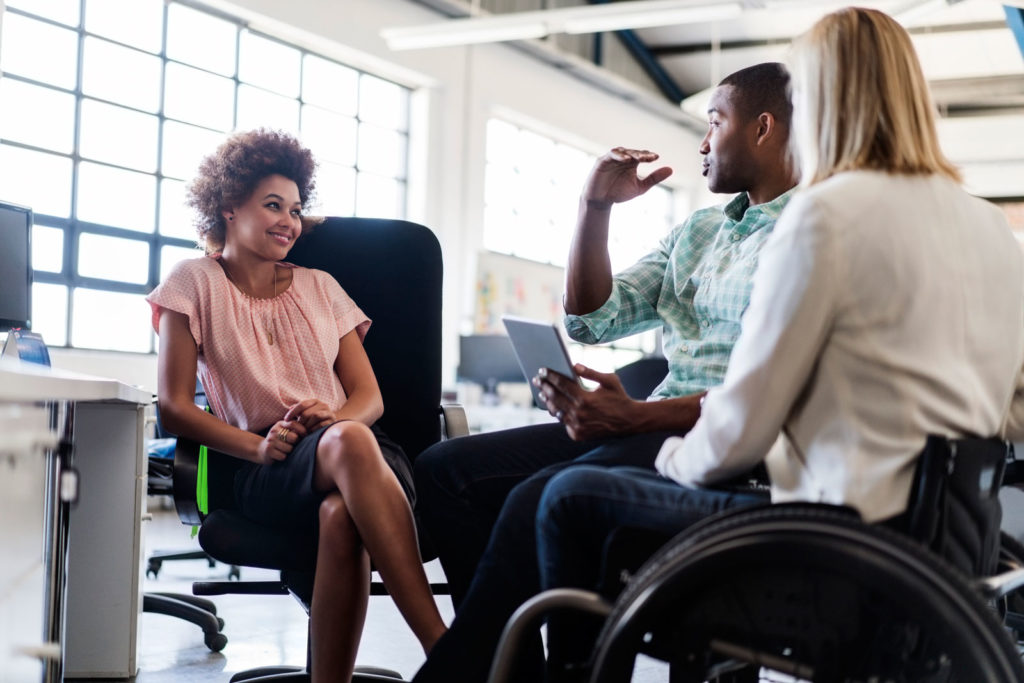 Business executive in wheelchair strategising with office colleagues