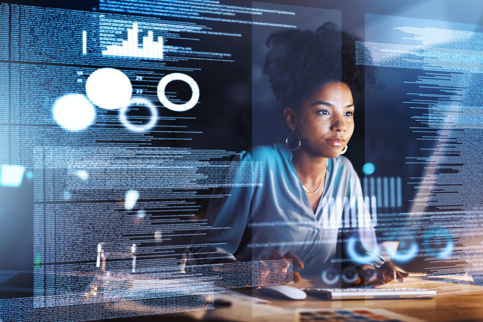 Young African woman sits in front of a computer coding