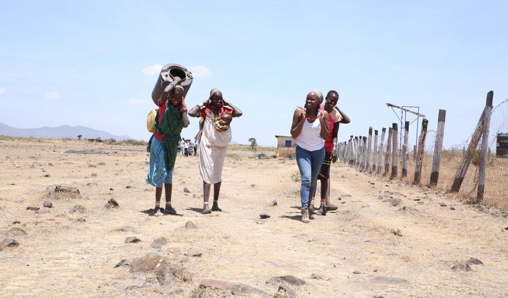 Reporter Verah Okeyo, wearing jeans, talks with Kenyans who live in Samburu County in the northern part of the country