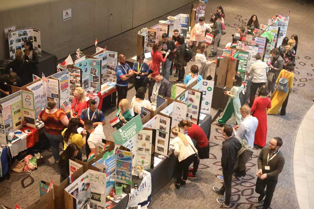 A conference room with a collection of stalls and people browsing from E2 2019 in Paris