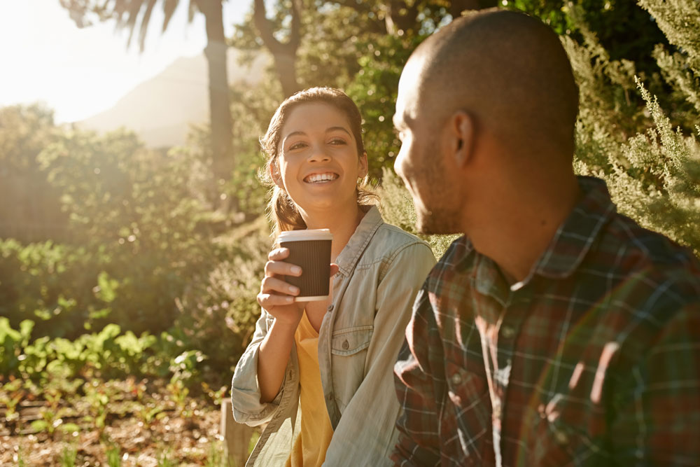 Young lady enjoying coffee with her partner in a garden-setting