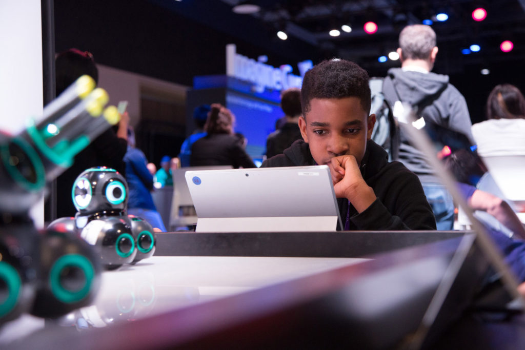 A young boy engaging with a tablet in the middle of a technology display