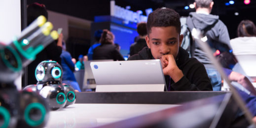 A young boy engaging with a tablet in the middle of a technology display