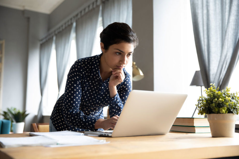 A business woman works on her laptop in the comfort of her own home.