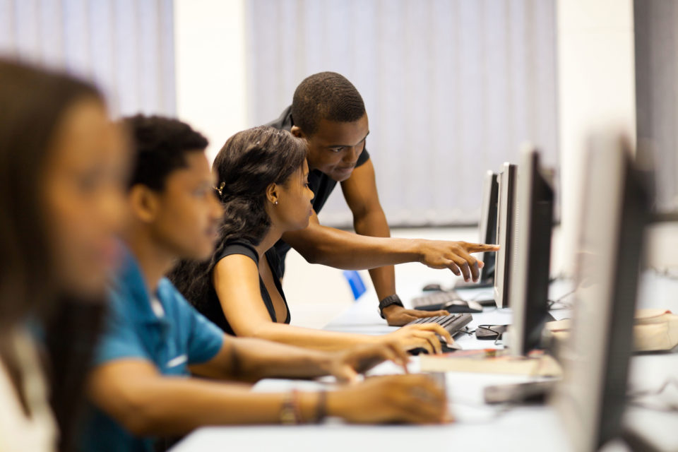 A mentor shows his students the ropes during a digital literacy session.