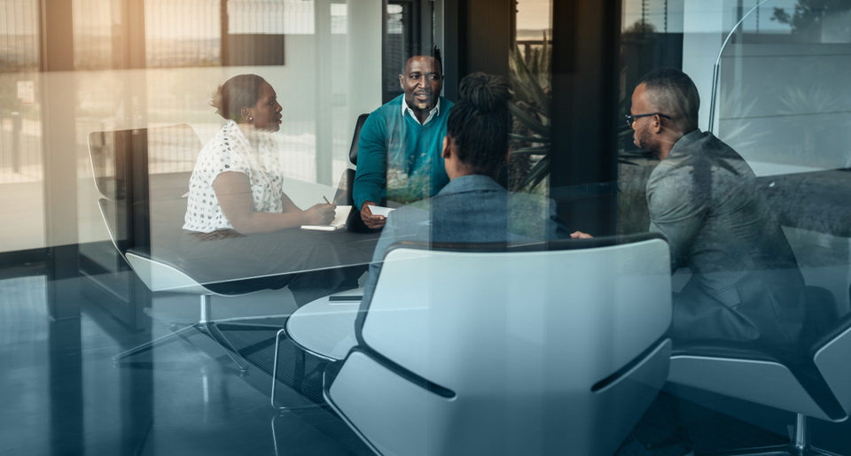 Professionals discussing business concerns in a small boardroom setting.