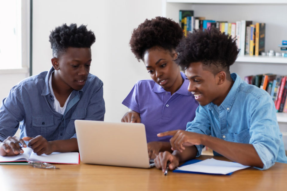Three students collaborating on a project in a library setting