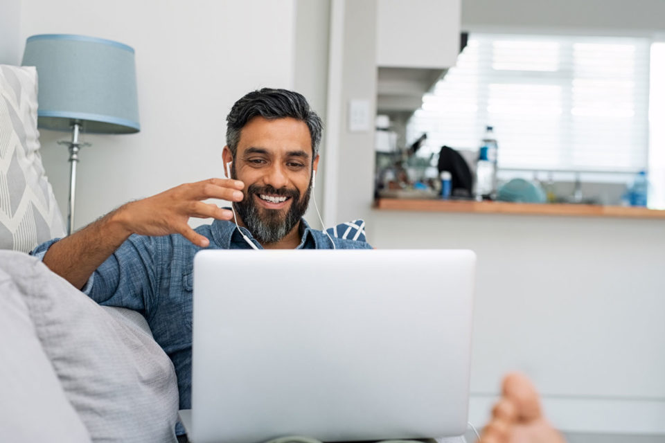 Middle Eastern man speaking on a video call from the comfort of his lounge.