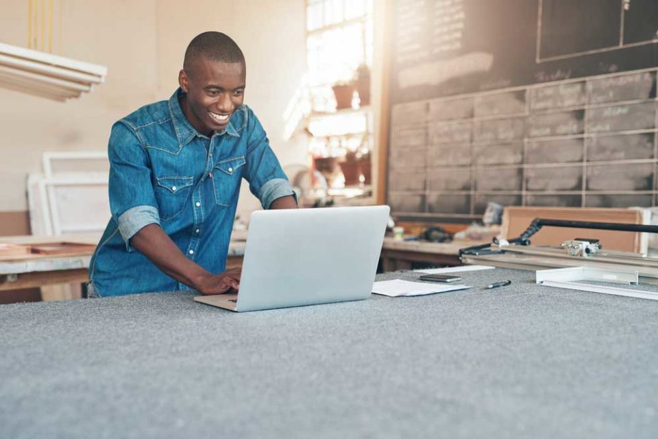 A young male entrepreneur using his laptop in a workshop setting.
